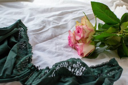 Photo for Women's green bra and pink roses on a white sheet - Royalty Free Image