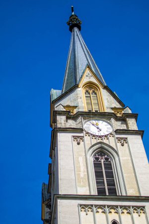 Die Turmspitze eines alten Kirchturms mit einer Uhr auf dem Gebiet der Abtei Admont.
