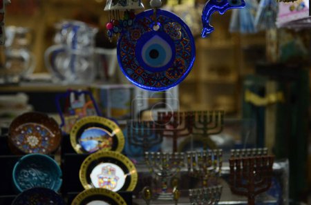 Photo for Nazar in East market. Blue and red Fatima eye close-up protective amulet against evil eye. Israeli and turkish souvenir. decorative glass blue souvenirs in the form of an eye - Royalty Free Image