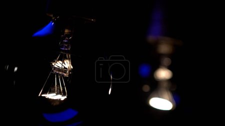Foto de Bombilla de cristal Tesla en la oscuridad. Hilo incandescente. Concepto: ahorro de energía, apagón, falta de electricidad, nueva idea, luz en la oscuridad - Imagen libre de derechos