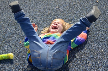 Photo for The little boy is naughty. The child lies on the ground and cries, yells. Bad behavior, childish whims. The child wants a toy. The boy lifted his legs up, hysterical - Royalty Free Image