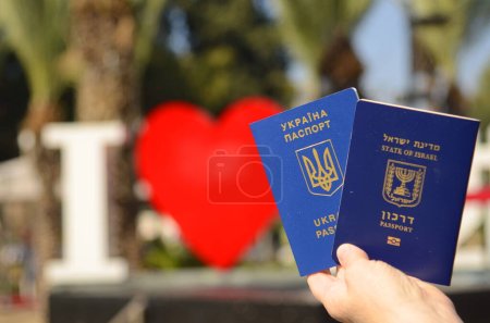 Foto de The concept of changing citizenship. Repatriation. Law of Return. Women's hands holding an Israeli passport and a Ukrainian passport - Imagen libre de derechos