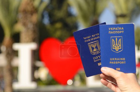 Foto de The concept of changing citizenship. Repatriation. Law of Return. Women's hands holding an Israeli passport and a Ukrainian passport - Imagen libre de derechos