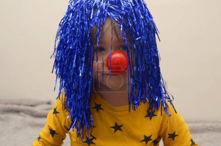 Téléchargez les photos : Little boy in a clown costume. Red nose and blue wig. Halloween, Purim - en image libre de droit