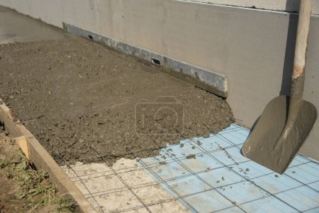 Photo for Freshly poured concrete screed with styrofoam insulation sheet and metal mesh for reinforcing. Close-up. - Royalty Free Image