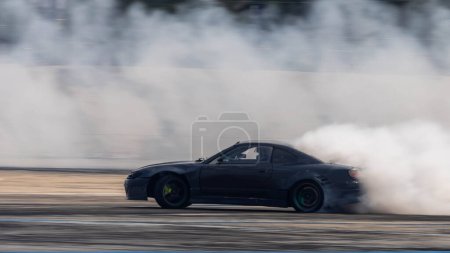 Blurred car drifting diffusion race drift car with lots of smoke from burning tires on speed track, Professional driver drifting car with lots of white smoke .