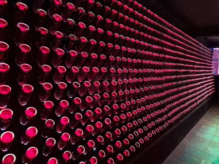 Foto de Antigua bodega con botellas rojas apiladas iluminadas en una bodega de Grecia - Imagen libre de derechos