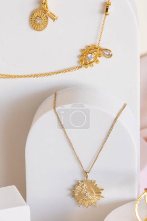 Elegant gold star shaped and other necklaces on white jewelry display stands. Beautiful girl accessories.