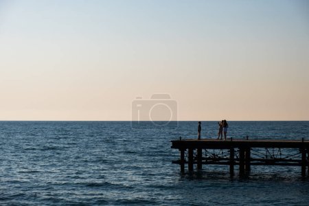 Téléchargez les photos : Silhouettes de personnes sur une jetée abandonnée à Argaka à Chypre. - en image libre de droit