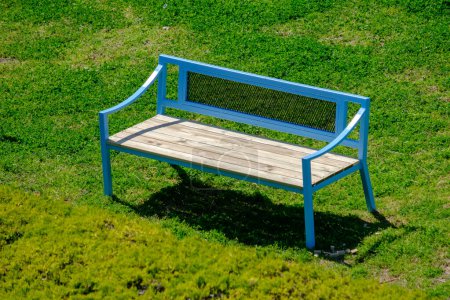 Blue bench on grass at a park. Spring scene. Suitable as a background
