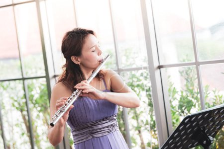 Photo for Flute classical instrument profestional player playing song.  A young and elegant Asian woman plays the flute. (Vintage Stye colour picture.) - Royalty Free Image