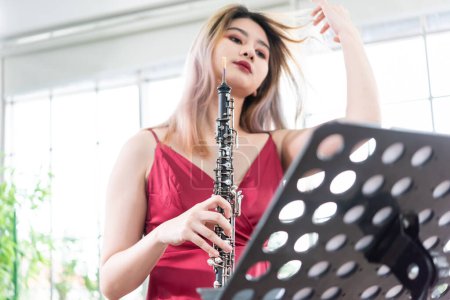 Beautiful young woman in a red dress playing the clarinet