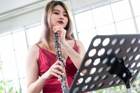 Belle jeune femme en robe rouge jouant de la clarinette
