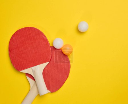 Téléchargez les photos : Paire de raquettes de tennis en bois pour ping-pong et balles en plastique sur fond jaune, vue de dessus - en image libre de droit