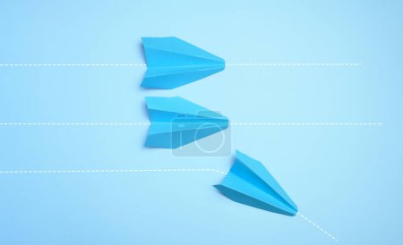 Photo for Three paper airplanes are moving forward, one turned sideways, representing the concept of individuality and non-standard thinking. - Royalty Free Image
