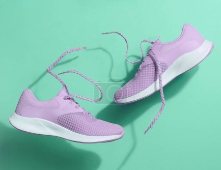 Photo for Purple women's sports sneakers with laces levitate on a green background. - Royalty Free Image