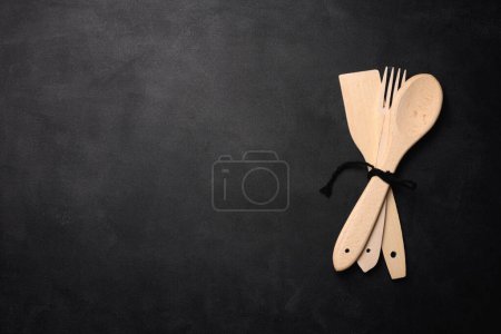 Foto de Tenedor y cuchara de madera vacía sobre un fondo negro, vista superior. Copiar espacio - Imagen libre de derechos