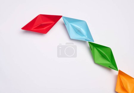 Group of paper boats on a white background.Concept of a strong leader in a team, manipulation of the masses, following new perspectives, collaboration and unification. Poster 654139100