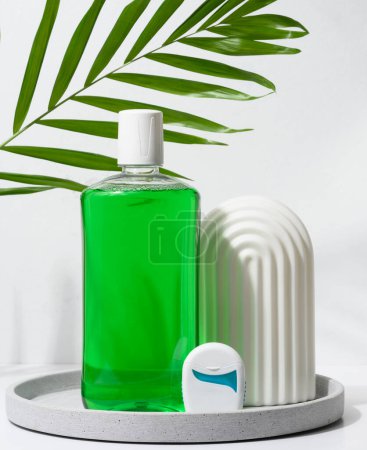 Téléchargez les photos : Rafraîchissant bain de bouche dans une bouteille en plastique transparent et fil dentaire sur un fond vert - en image libre de droit