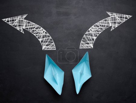 Photo for Two paper boats are moving in different directions on a black background, top view - Royalty Free Image