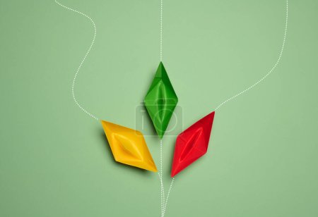 Paper boats on a green background with paths of movement, representing the concept of individuality. Top view