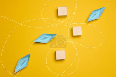 Paper boats and the trajectory of movement avoiding obstacles, yellow background