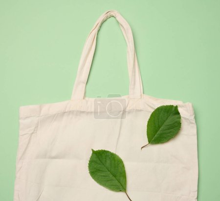 Foto de Bolso textil beige vacío sobre fondo verde, rechazo de bolsas de plástico, disposición plana, cero residuos - Imagen libre de derechos