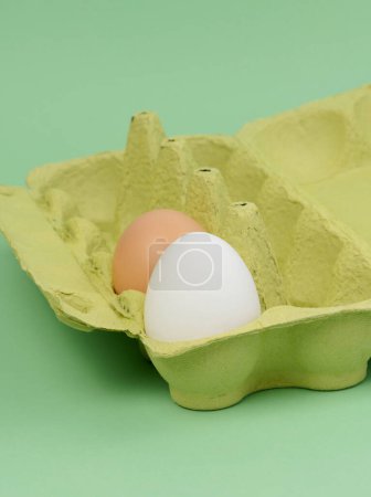 Foto de Dos huevos de pollo en una caja de papel sobre un fondo verde, de cerca - Imagen libre de derechos