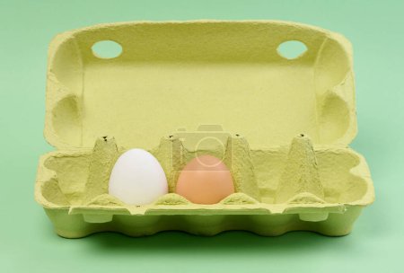 Foto de Dos huevos de pollo en una caja de papel sobre un fondo verde - Imagen libre de derechos