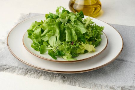 Foto de Hojas de lechuga verde fresca en un plato blanco sobre la mesa, comida saludable - Imagen libre de derechos