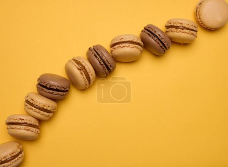 Foto de Macarrones de chocolate sobre fondo amarillo, postre. Vista superior - Imagen libre de derechos