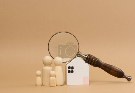 Foto de Lupa y una familia de figuras de madera en el fondo de una casa, el concepto de búsqueda de alquiler de bienes raíces, hipoteca - Imagen libre de derechos