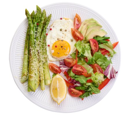 Foto de Placa redonda con espárragos cocidos, huevo frito, aguacate y ensalada de verduras frescas, vista superior - Imagen libre de derechos