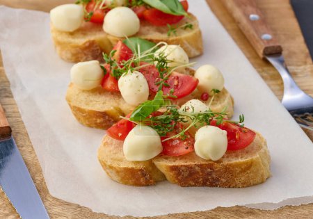 Foto de Mozzarella redonda, tomates cherry y microgreens en un pedazo de pan blanco, un sándwich saludable - Imagen libre de derechos