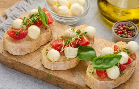 Foto de Mozzarella redonda, tomates cherry y microgreens en un pedazo de pan blanco, un sándwich saludable, de cerca - Imagen libre de derechos