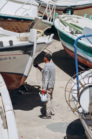 Téléchargez les photos : Batroun, Liban 24.04.2023 : Un homme peint un yacht dans le port de Batroun - en image libre de droit
