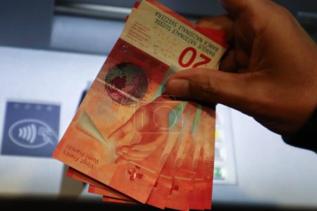 Téléchargez les photos : Gros plan de plusieurs billets de banque en francs suisses près du guichet automatique - en image libre de droit