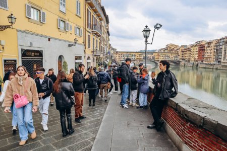 Foto de Florencia, Italia - 31 diciembre, 2023: Gente cerca del río Arno en el centro de Florencia, con el Ponte Vecchio visible en el fondo - Imagen libre de derechos