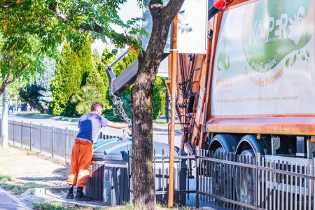 Photo for Podgorica , Montenegro - August 08, 2023: A scavenger throws garbage down the street into a garbage truck - Royalty Free Image