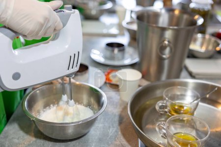 Téléchargez les photos : Mains en utilisant un mélangeur électrique pour faire de la crème fouettée. processus de cuisson sur le fond de la cuisine - en image libre de droit