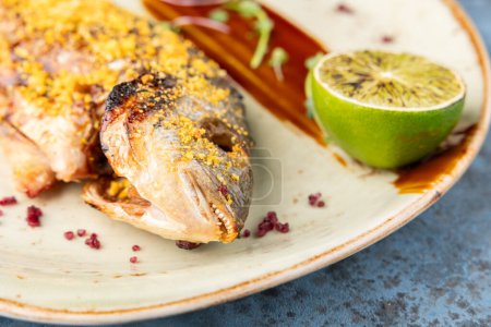 délicieux dorado grillé ou poisson de daurade avec citron vert, microgreens et sauce sur plateau blanc sur table bleue