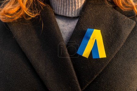 Photo for Girl in a black coat with a yellow-blue ribbon. Close-up. National symbol of Ukraine - Royalty Free Image