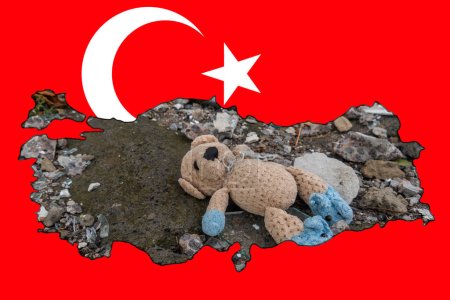 A children's toy (teddy bear) lies on fragments of glass and concrete. Picture in the form of a map of Turkey on the background of the national flag of Turkey. Earthquake in Turkey
