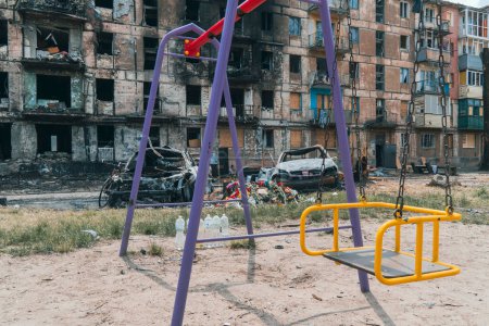 Photo for An empty children's playground next to a residential building destroyed by rocket fire. War in Ukraine. Terror of the civilian population - Royalty Free Image