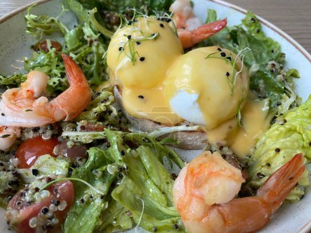 Foto de Desayuno saludable. Huevos Benedict con quinua, lechuga, camarones con salsa. Primer plano, enfoque selectivo. - Imagen libre de derechos