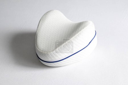 Foto de Orthopedic knee pillow for comfortable sleep. The pillow lies on the bed - Imagen libre de derechos