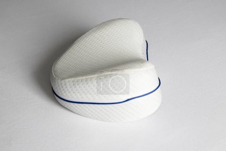 Foto de Orthopedic knee pillow for comfortable sleep. The pillow lies on the bed. - Imagen libre de derechos