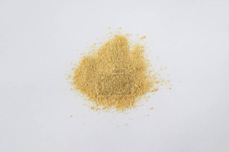Non-activated nutritional yeast flakes are scattered on a white background
