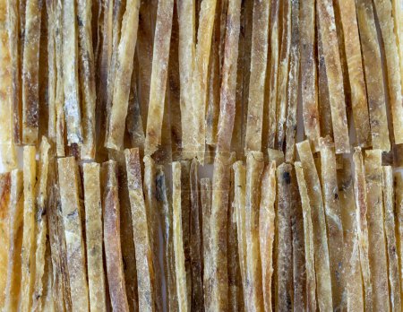 Téléchargez les photos : Dried salted tuna meat strips sliced or stacked in strips all over the background. An elite beer snack. Close-up - en image libre de droit