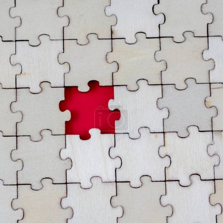 Téléchargez les photos : Absence wooden puzle on a red background. Missing Piece. The concept of lack and incompleteness. Square Photo. - en image libre de droit